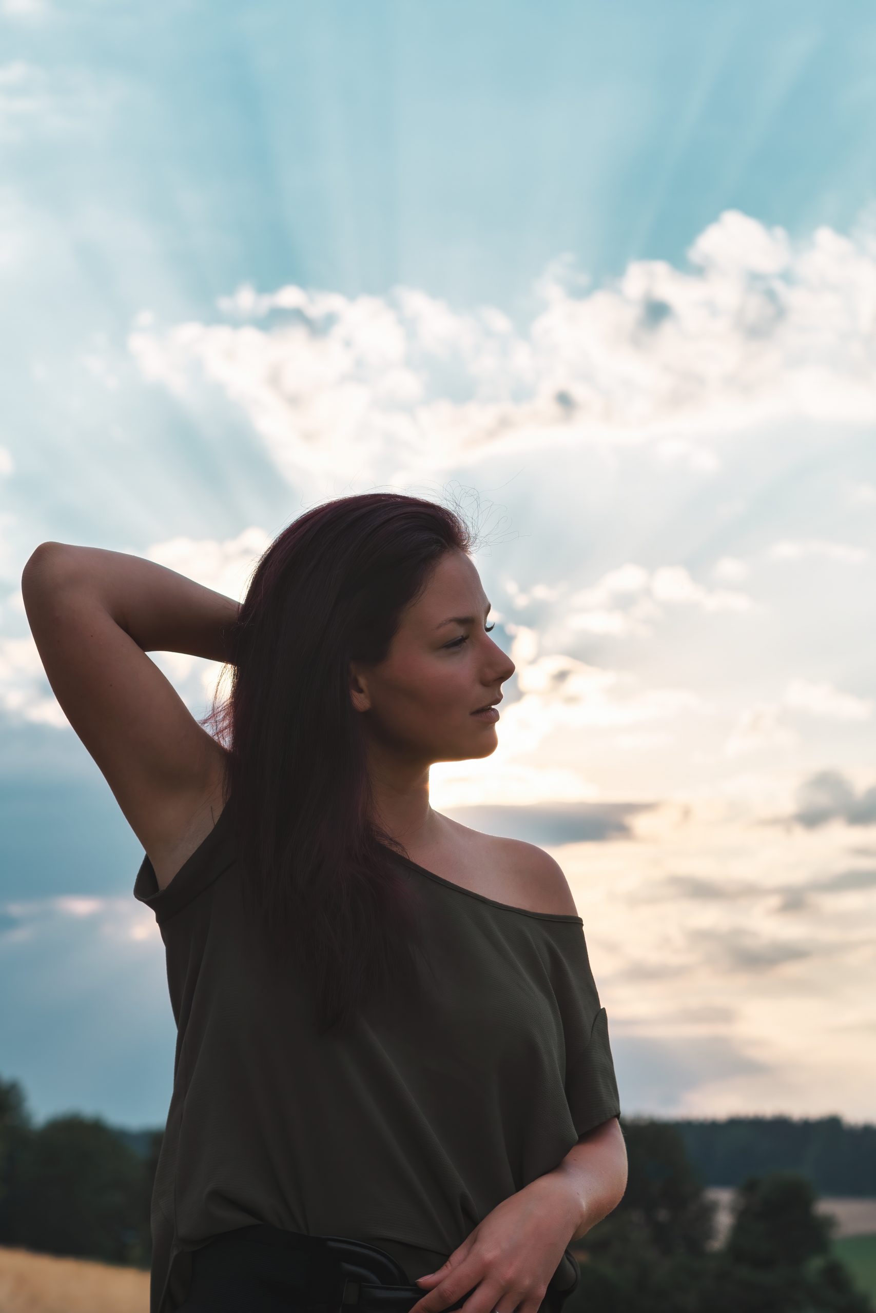 Frau im Gegenlicht vor Sonnenstrahlen und Wolken