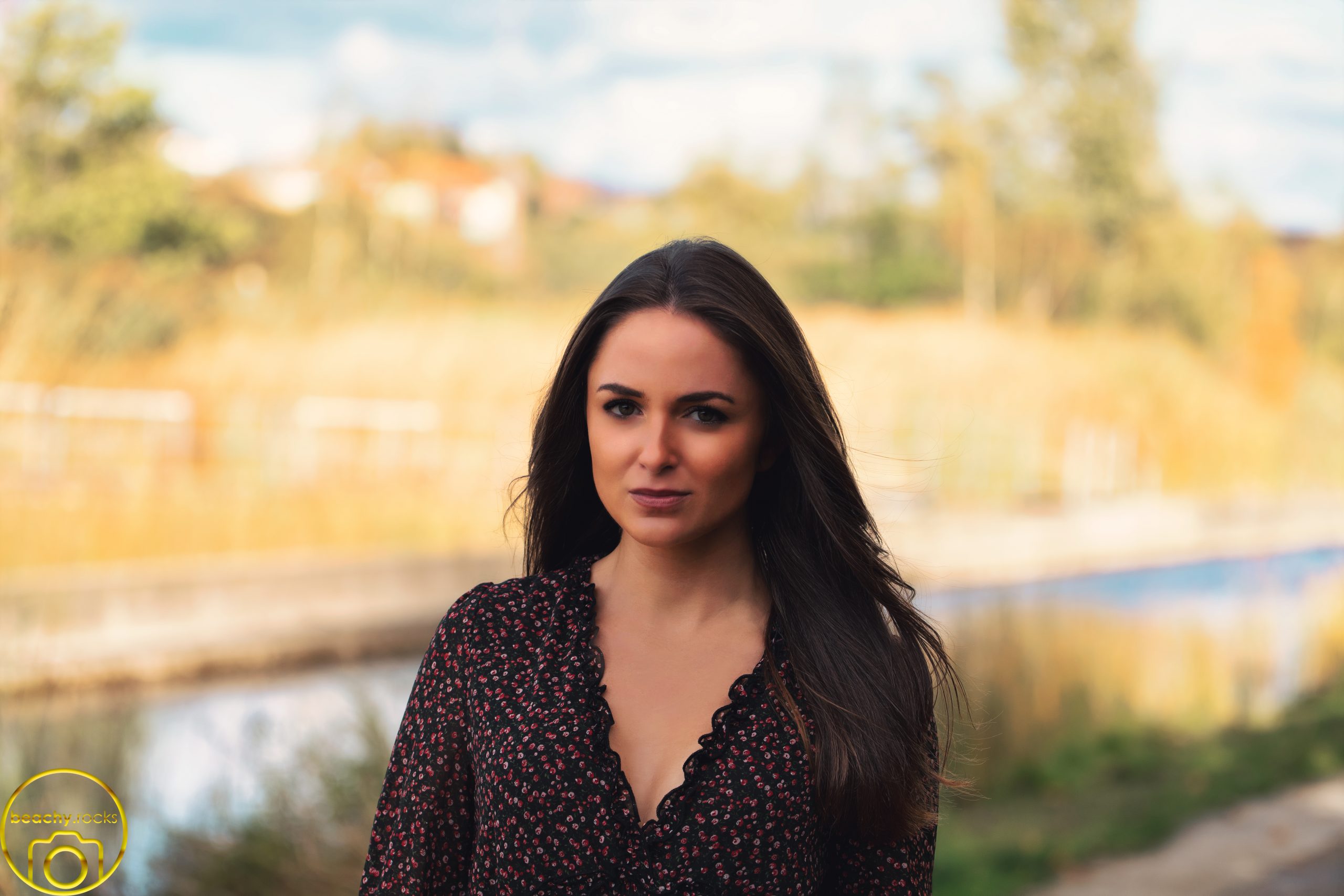 Frau im Kleid vor einem Teich in herbstlicher Landschaft