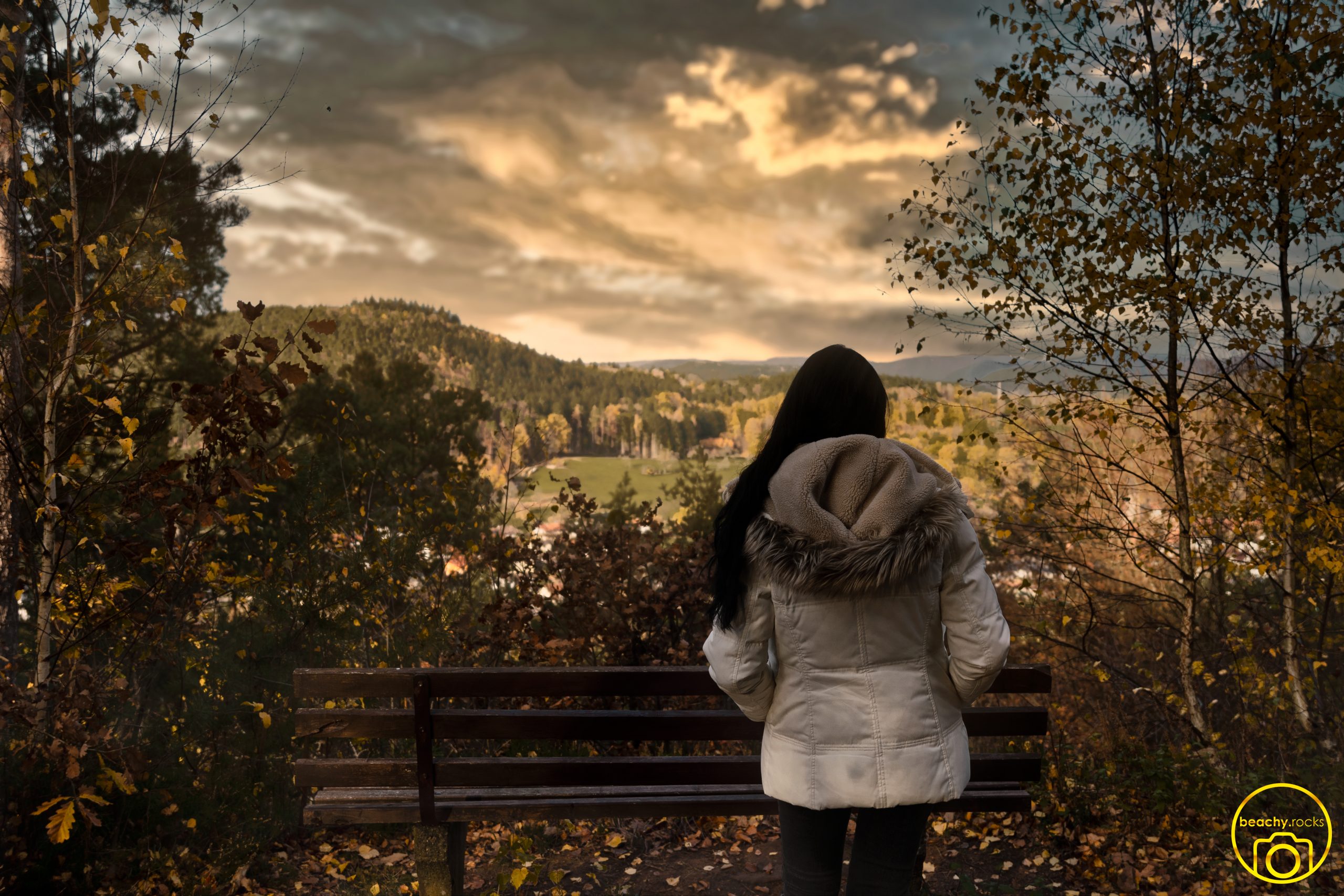Person auf einer Bank mit Blick über herbstliche Hügel
